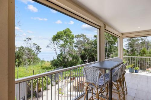 a balcony with a table and chairs and a view at Foreshore Retreat in Corinella