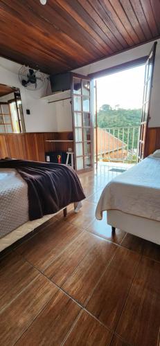 a bedroom with a large bed and a balcony at Pousada Araucária Suítes in Campos do Jordão