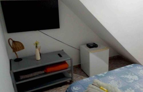 瓜魯雅的住宿－Suite Guarujá，卧室配有一张床,墙上配有电视。