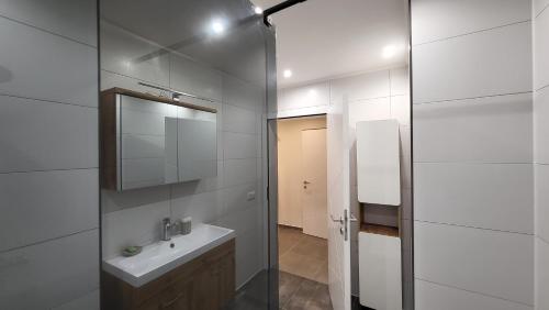 ein weißes Badezimmer mit einem Waschbecken und einem Spiegel in der Unterkunft Quiet House - 10 min away from Cologne in Bergisch Gladbach