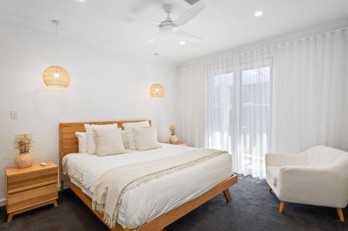 a white bedroom with a bed and a chair at Belle Escapes - Golf Villa by the Sea in Grange