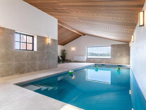 a swimming pool in a house with a wooden ceiling at Lindehoeve in Turnhout