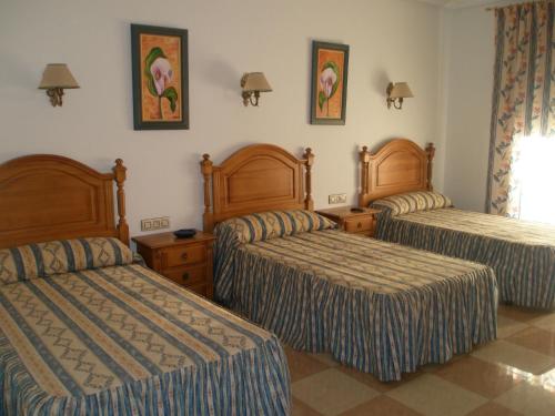 um quarto de hotel com três camas num quarto em Hostal Los Rosales em Alcaraz