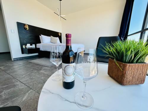 NUMA Wine Suites في إنسينادا: زجاجة من النبيذ وكأسين من النبيذ على الطاولة