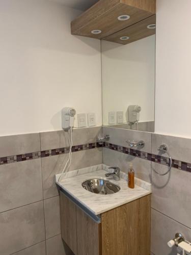 a bathroom with a sink and a mirror at Villa Edén Departamento 1 Dormitorio con Cochera in La Falda