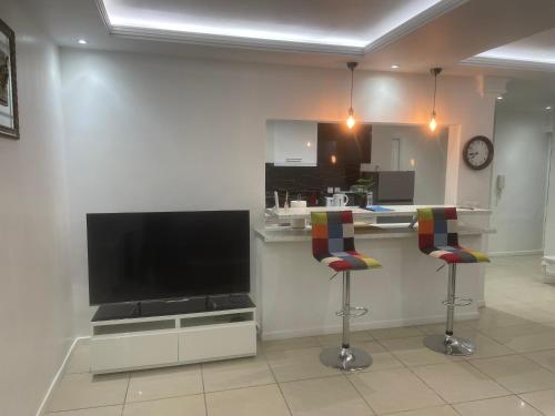 - une cuisine avec une télévision et deux tabourets de bar dans l'établissement SPACIEUX 3 PIECES PRÉS DE ROISSY,PARC ASTERIX ET PARIS, à Le Thillay