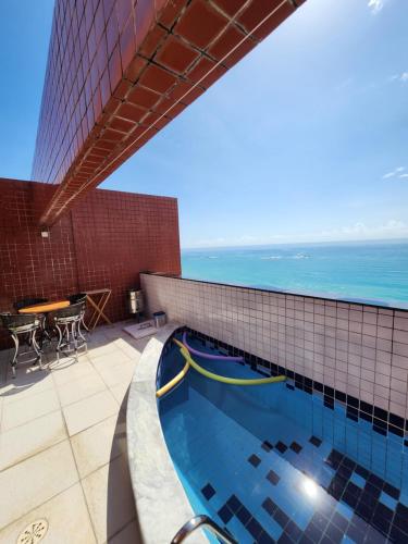 uma piscina no topo de um edifício com o oceano em Cobertura Duplex Beira Mar 3 quartos em Maceió