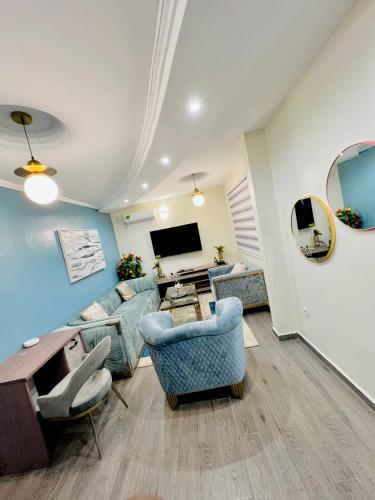 uma sala de estar com mobiliário azul e uma televisão de ecrã plano em The Jumeirah Guest Home em Iaundé