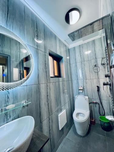 a bathroom with a sink and a toilet and a mirror at The Jumeirah Guest Home in Yaoundé