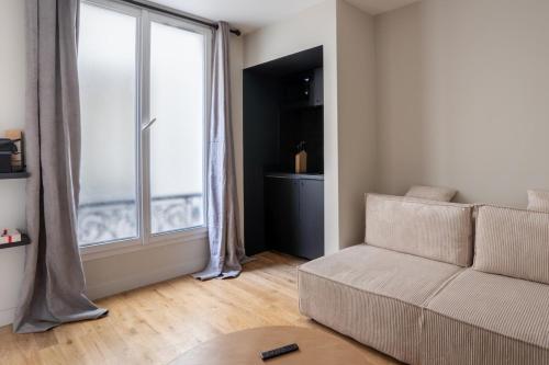 un salon avec un canapé et une grande fenêtre dans l'établissement Modern and elegant 1BD Apartment near Montmartre, à Paris