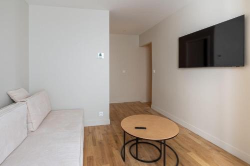 un salon avec une table et une télévision au mur dans l'établissement Modern and elegant 1BD Apartment near Montmartre, à Paris