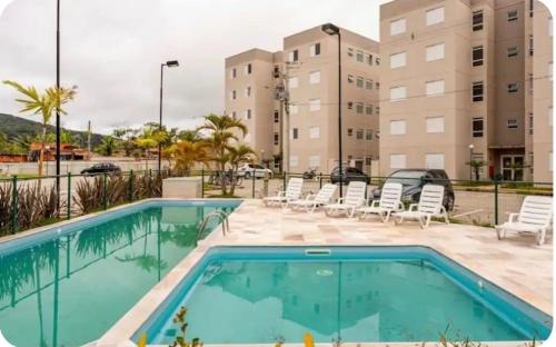 basen z krzesłami i budynek w obiekcie Apartamento Residencial HM enseada w mieście Guarujá