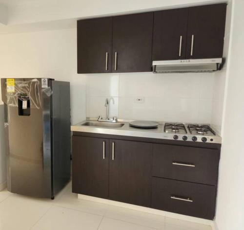 a kitchen with brown cabinets and a stainless steel refrigerator at Apartamento con excelente vista in Cúcuta