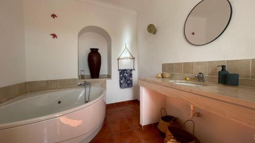 a bathroom with a tub and a sink and a mirror at Pátio do Alqueva - Alojamento Local in Granja