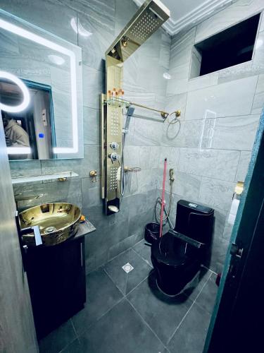 a bathroom with a black toilet and a sink at The Jumeirah Guest Home in Yaoundé