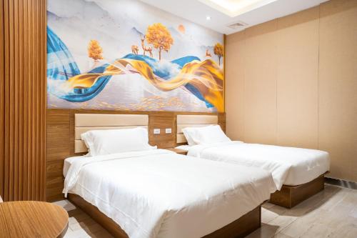 two beds in a room with a painting on the wall at Home me Hotel in Manila
