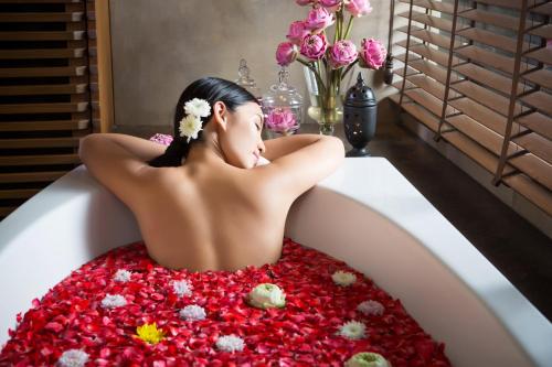 a woman laying in a bath tub covered in flowers at Lancaster Bangkok in Bangkok