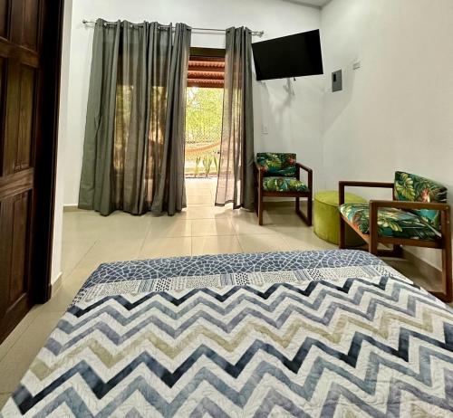 a bedroom with a bed and two chairs and a television at Cabañas Quebrada del Pueblo in Dolega