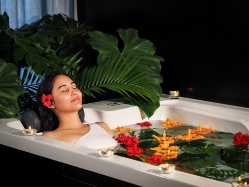 a woman laying in a bath tub with flowers at Le Tahiti by Pearl Resorts in Papeete