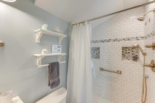a white bathroom with a shower and a toilet at Lakefront Highland Home with Dock about 2 Mi to Milford! 