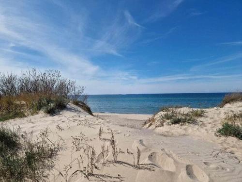 a sandy beach with the ocean in the background at Summer House by Lake Jamno near the Sea in Łazy
