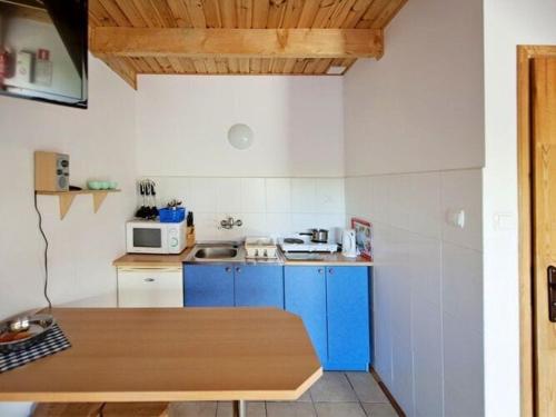 a small kitchen with blue cabinets and a microwave at Storey holiday house, Sarbinowo in Sarbinowo