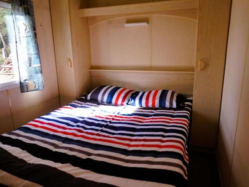 a bed in a small room with a striped blanket at Dutch houses for 4 people, close to the sea in Łazy