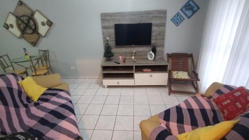 a living room with two couches and a flat screen tv at Apartamento beira mar Centro da cidade WiFi grátis in Mongaguá