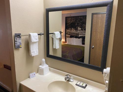 a bathroom with a sink and a mirror and a bed at Super 8 by Wyndham Winfield-Quail Ridge Area in Winfield