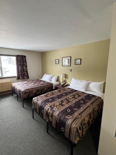 Habitación de hotel con 2 camas y ventana en Minnedosa Inn, en Minnedosa