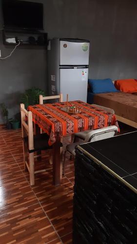 Maimara Host في مايمارا: طاولة مع كراسي وثلاجة في الغرفة