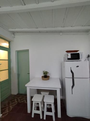 a white table with two stools and a white refrigerator at CasaLins in Chascomús