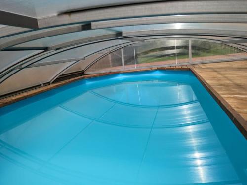 une piscine avec de l'eau bleue dans un immeuble dans l'établissement Gîte de charme avec piscine chauffée, salle de jeux, et salle de fitness proche du lac de Rillé - FR-1-381-563, à Rillé