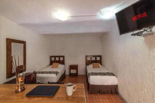 a room with two beds and a tv on the wall at Estudio Doble, 2 Camas en el corazón de Chapalita 13 in Guadalajara