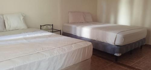 two beds sitting next to each other in a room at Residencial derosas 