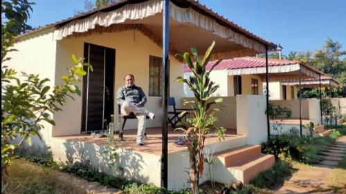 a man sitting in a chair in front of a house at Ranthambore Jungle Home in Khilchipur