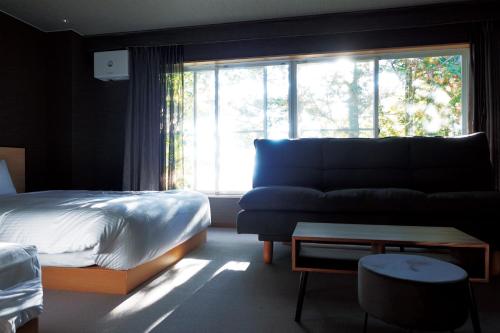 a bedroom with a bed and a couch and a window at Resort Hotel RAKI House Nasu in Nasu