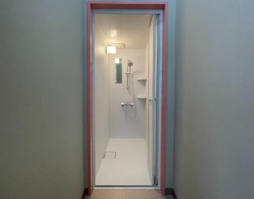 un bagno con doccia con porta in vetro di LivingAnywhere Commonsうるま twin bed room - Vacation STAY 88989v a Uruma