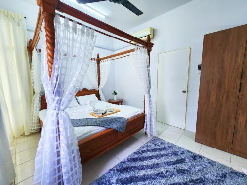 a bedroom with a canopy bed with a blue rug at Ipoh - Apartment Casa Klebang 1 Fully Air-Con Suite in Chemor