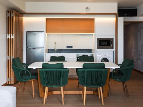 a kitchen with a table and green chairs at Le Tahiti by Pearl Resorts in Papeete