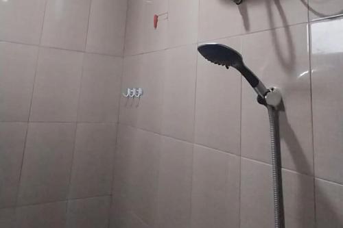 a shower with a shower head in a bathroom at Wisma Merdeka Syariah RedPartner in Palembang