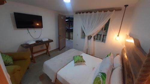 a living room with a white couch and a television at AZAHARES HOTEL Y CAFÉ in Manizales