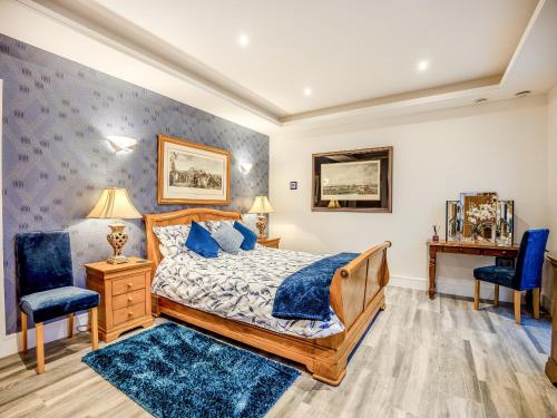a bedroom with a bed and two blue chairs at The Paddocks Retreat in North Thoresby