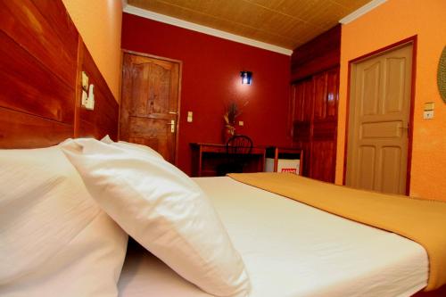 - une chambre avec un lit blanc aux murs rouges dans l'établissement Hotel Le Prince, à Cotonou