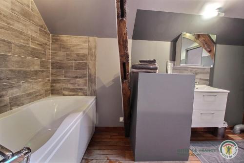 een badkamer met een bad, een wastafel en een spiegel bij Duke du manoir in Paimpol