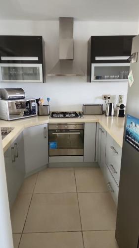 a kitchen with white cabinets and a stove top oven at Idyllic Beach Apartment in Bain Boeuf