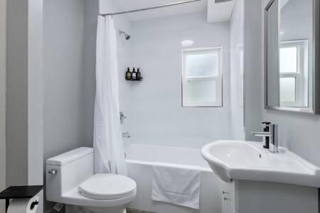 a white bathroom with a toilet and a sink at Spacious 4 BR House in Park Drive in Vancouver