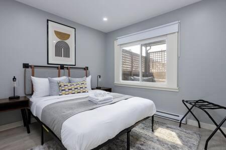 a white bedroom with a bed and a window at Spacious 4 BR House in Park Drive in Vancouver