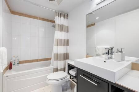 a white bathroom with a sink and a tub and a toilet at Heart of Downtown Luxury 2BR Condominium in Vancouver