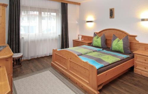 ein Schlafzimmer mit einem Holzbett mit grünen und blauen Kissen in der Unterkunft Beautiful Apartment In Aschau Im Zillertal With House A Mountain View in Aschau